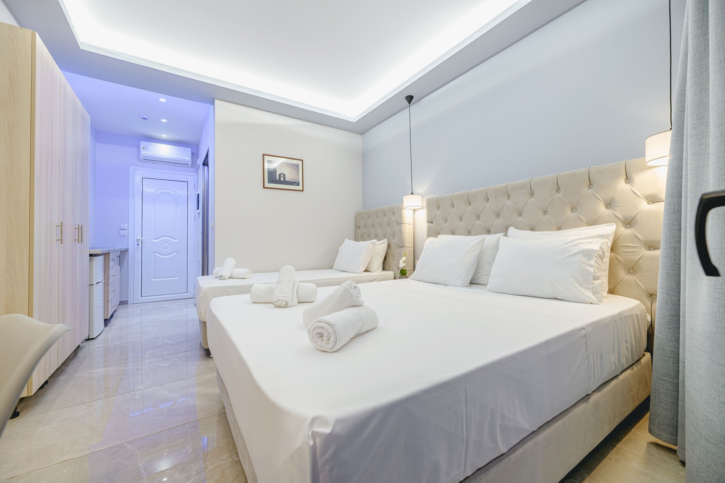 Una habitación de hotel moderna con una cama grande, una mesita de noche, un armario y un baño visible a través de una puerta abierta.