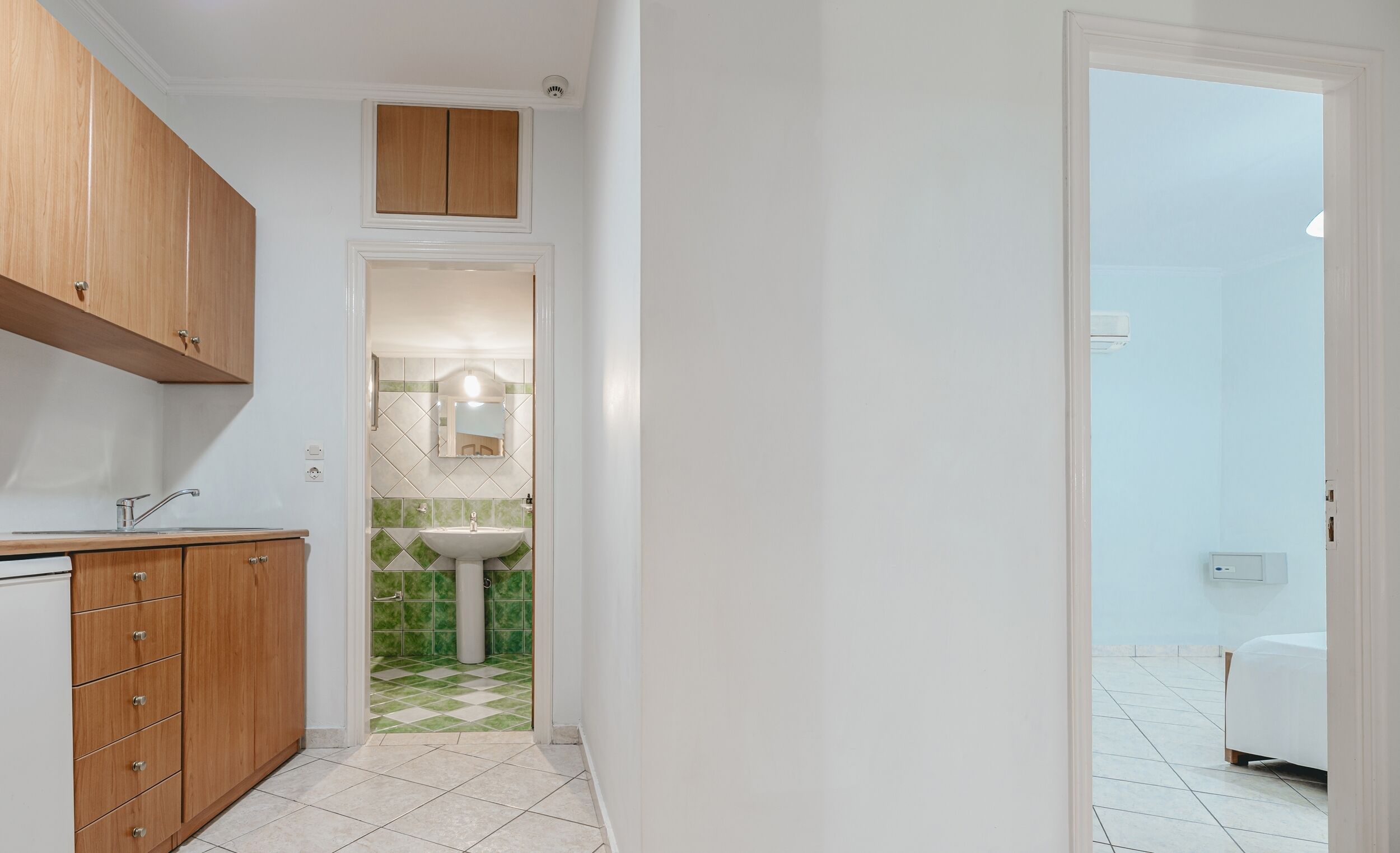 A narrow hallway leading to a bathroom with a sink and mirror.