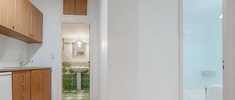 A narrow hallway leading to a bathroom with a sink and mirror.
