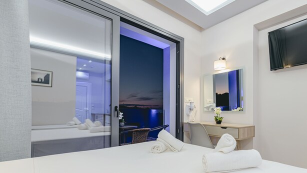Una habitación de hotel moderna con una cama, un escritorio, una silla, un baño con espejo y vistas al exterior.
