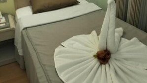 Et hotelværelse med en seng, et natbord og en lampe på væggen.