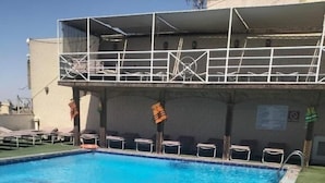 En swimmingpool med klart, blåt vand, omgivet af liggestole og en redningskrans.