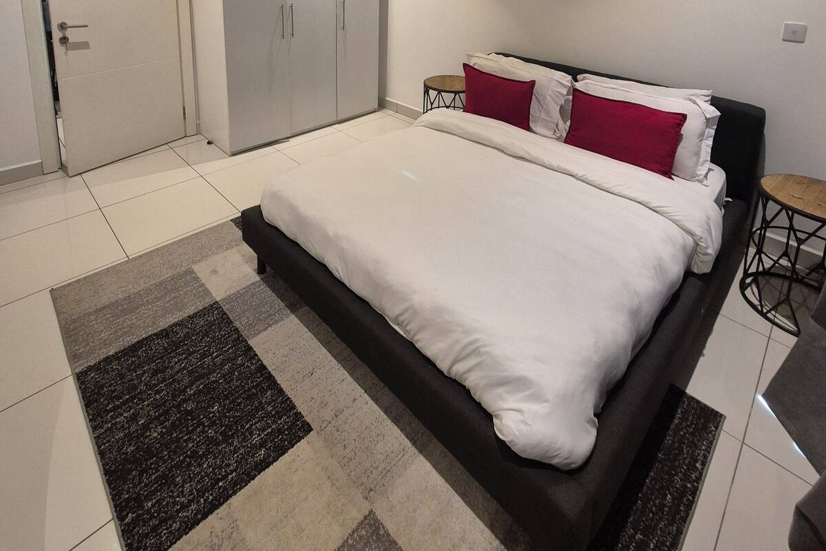 Une chambre moderne avec un grand lit, une armoire et une petite table.