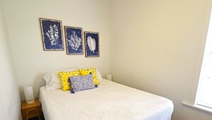 A bedroom with a wooden bed, white bedding, and three framed botanical prints on the wall. - The Perfect Getaway 2-bedroom apartment in wonderful Sandusky with WiFi, AC (Sandusky)