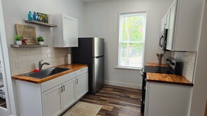 A modern kitchen with white cabinets, a stainless steel refrigerator, wooden countertops, and a window with blinds. - The Perfect Getaway 2-bedroom apartment in wonderful Sandusky with WiFi, AC (Sandusky)