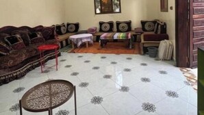A living room with a patterned floor, a sofa set, a small table, and a ceiling light. - At Sondos (Marrakech)
