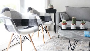 A modern living room with two chairs, a sofa, a small table with potted plants, and a window providing natural light. - Agapaki Studios (Neos Marmaras)