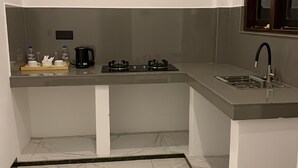 Una cocina compacta con estufa a gas, un lavamanos y una cafetera.