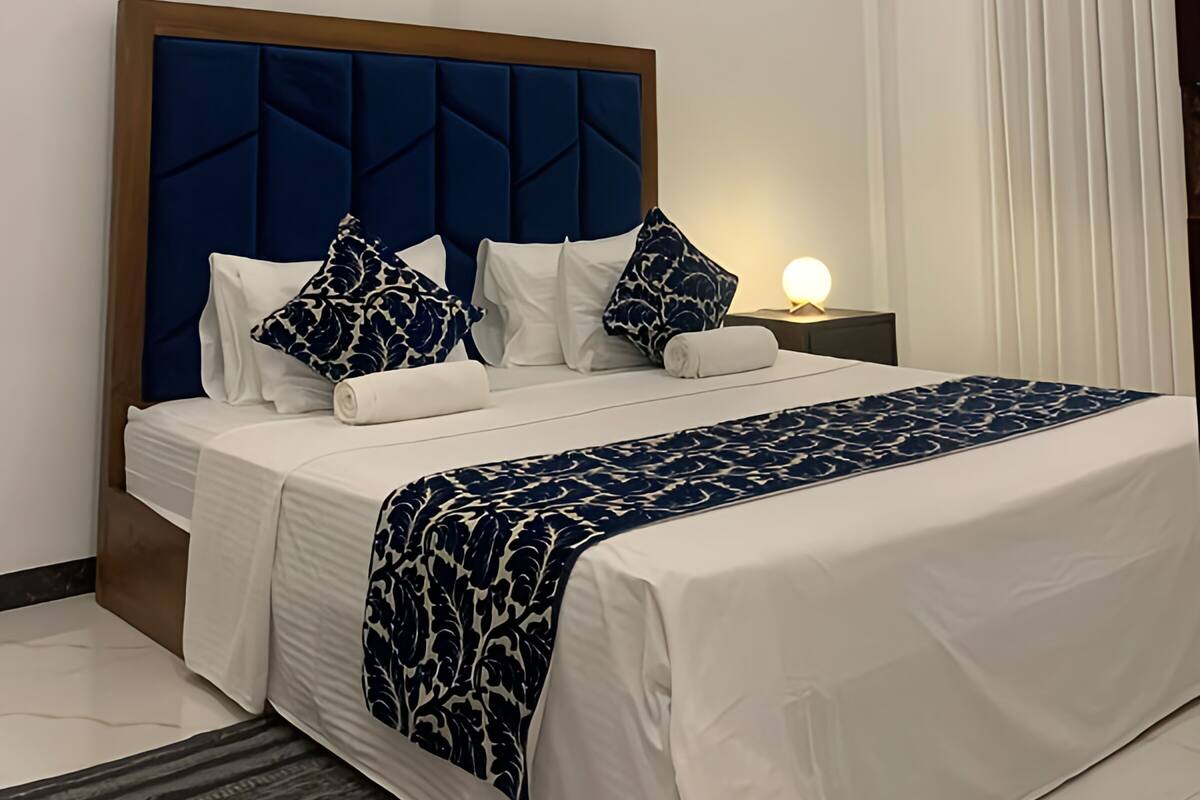 Hotelkamer met een bed, plafondventilator, nachtkastje en raam met gordijnen.
