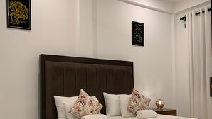 Un dormitorio con una cama grande, un ventilador de techo y dos obras de arte colgadas en la pared.