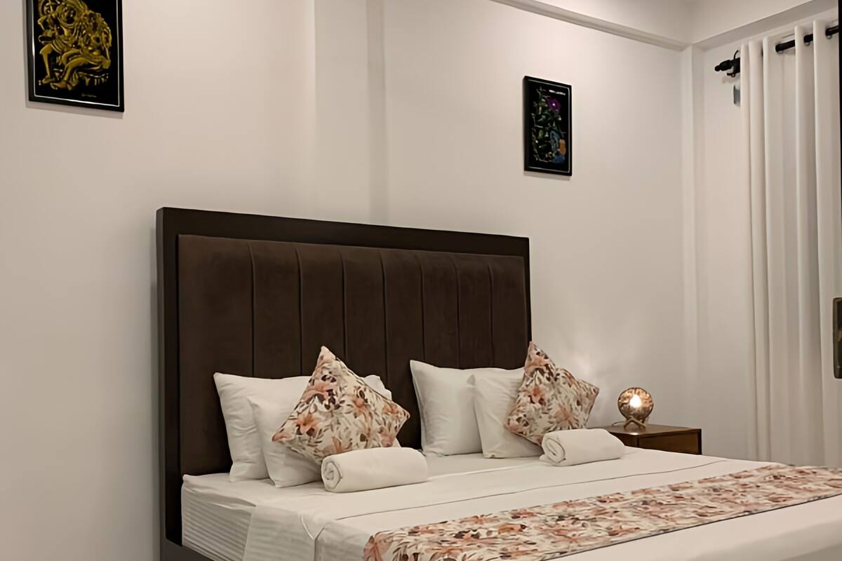 Een slaapkamer met een groot bed, een plafondventilator en twee kunstwerken aan de muur.