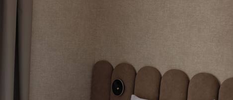 A hotel room with a bed, a nightstand, a wall-mounted air conditioner, and a curtain.