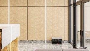 Un espace d’accueil moderne avec un mur revêtu de panneaux en bois, un comptoir d’accueil, un coin salon et une porte vitrée donnant sur l’extérieur.