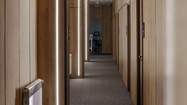 Un couloir aux murs lambrissés, avec un radiateur et un sol recouvert de moquette.