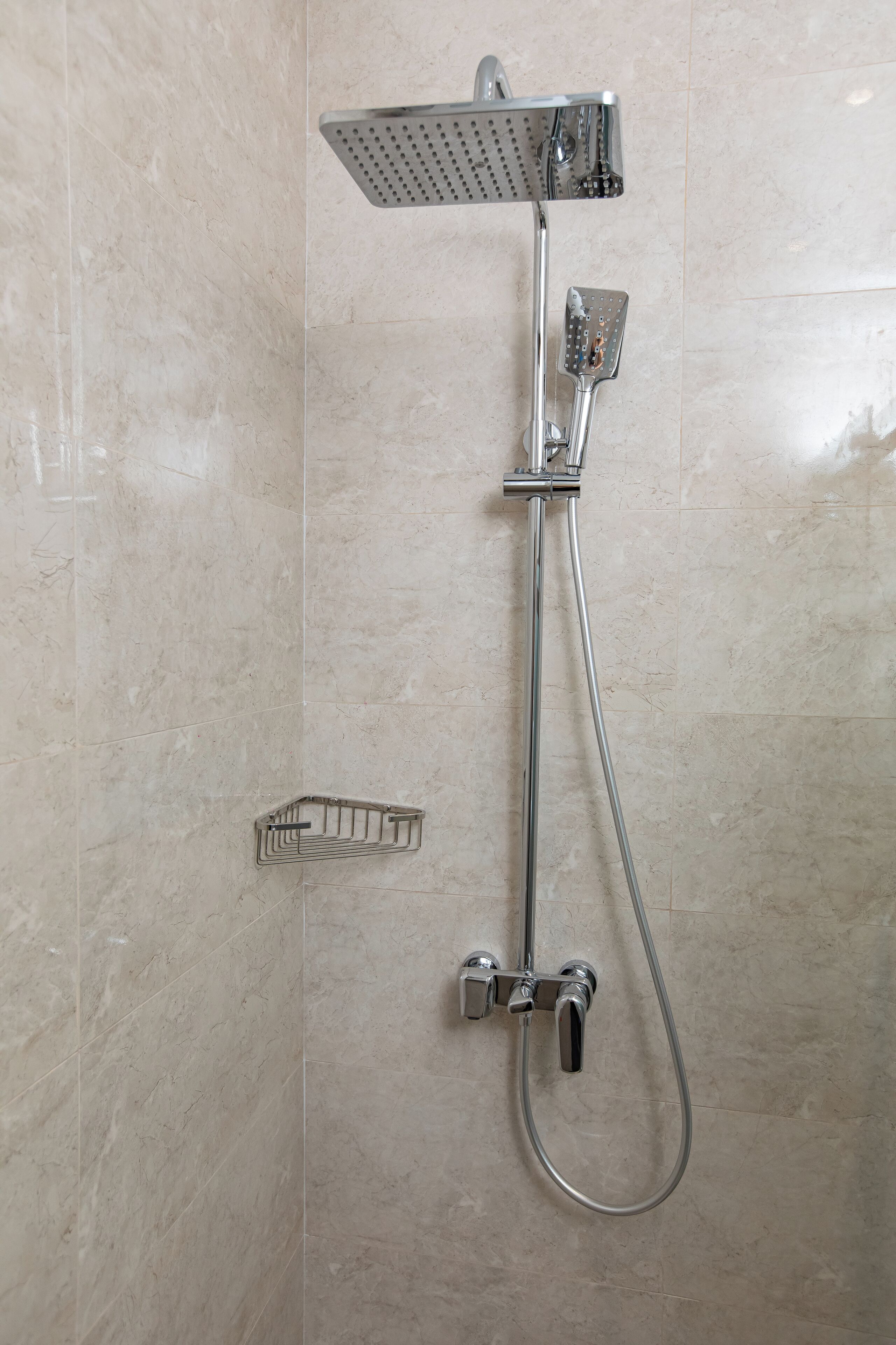 Une douche équipée d’un pommeau de douche à main et d’un pommeau de douche fixe fixé au mur.