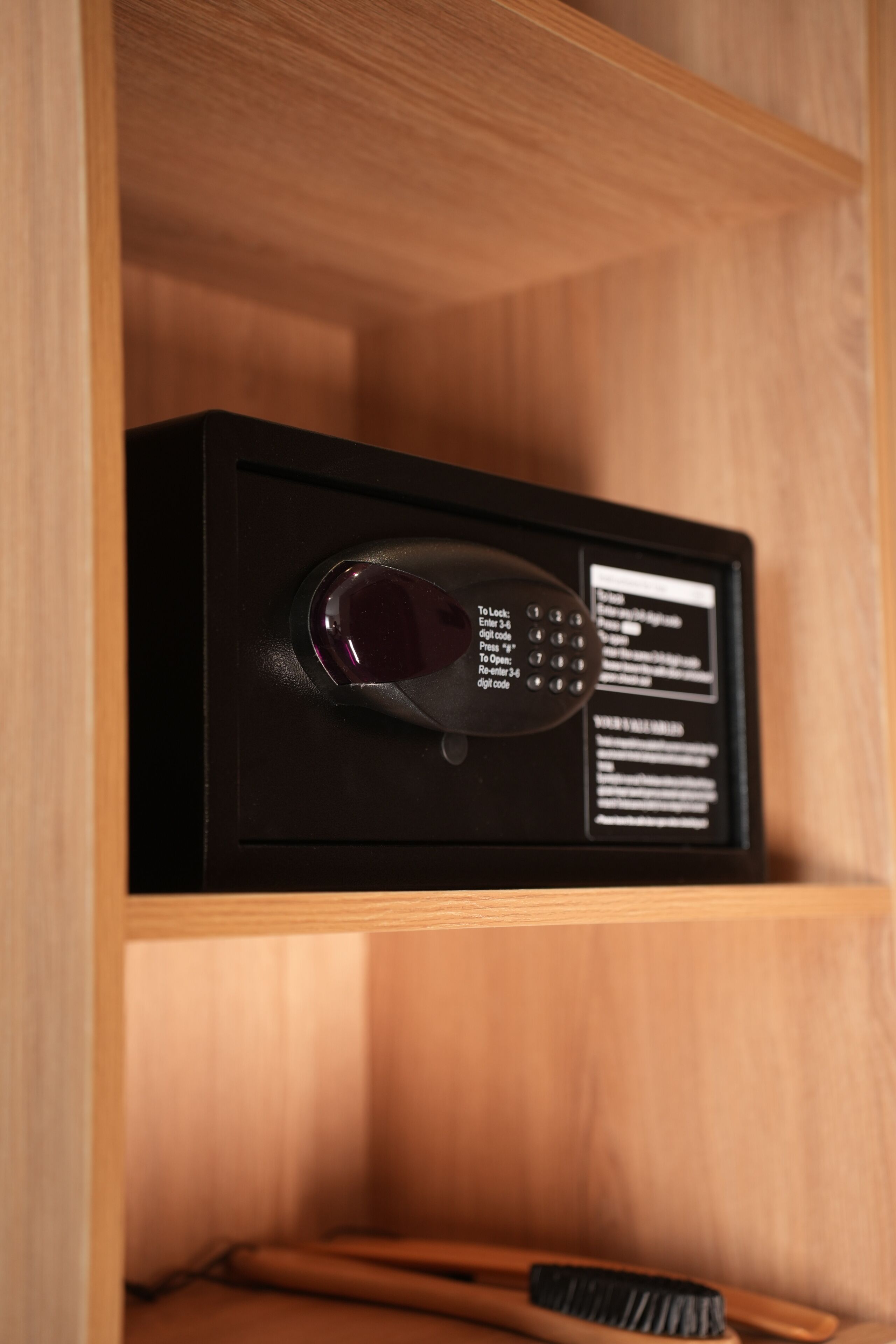 A black electronic device with a keypad and a display screen in a wooden cabinet.