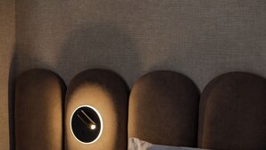 Un lit avec une tête de lit ornée d’un luminaire circulaire.