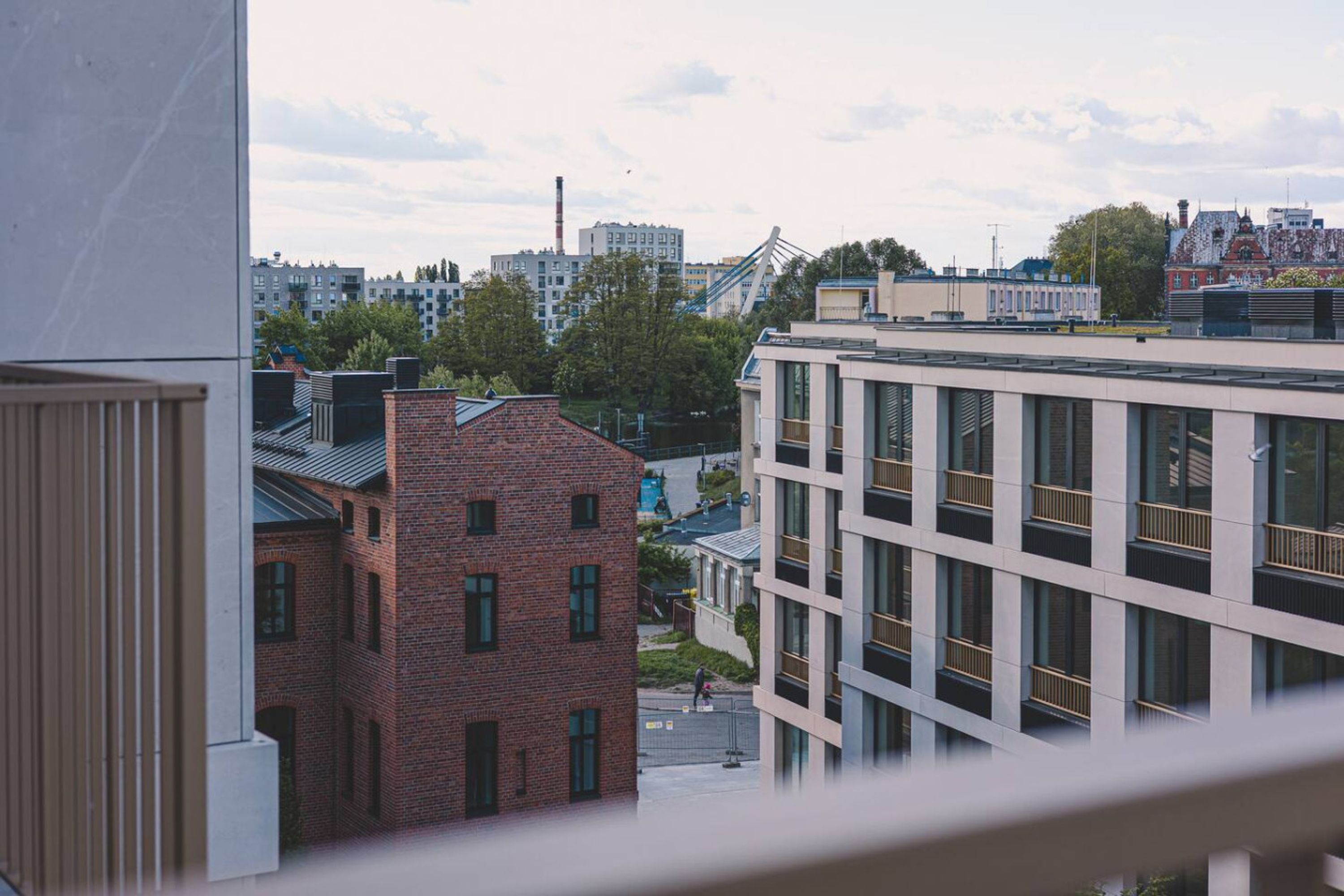 A modern urban landscape with a mix of residential and commercial buildings, including a prominent white building with large windows and a brick structure with a sloped roof.