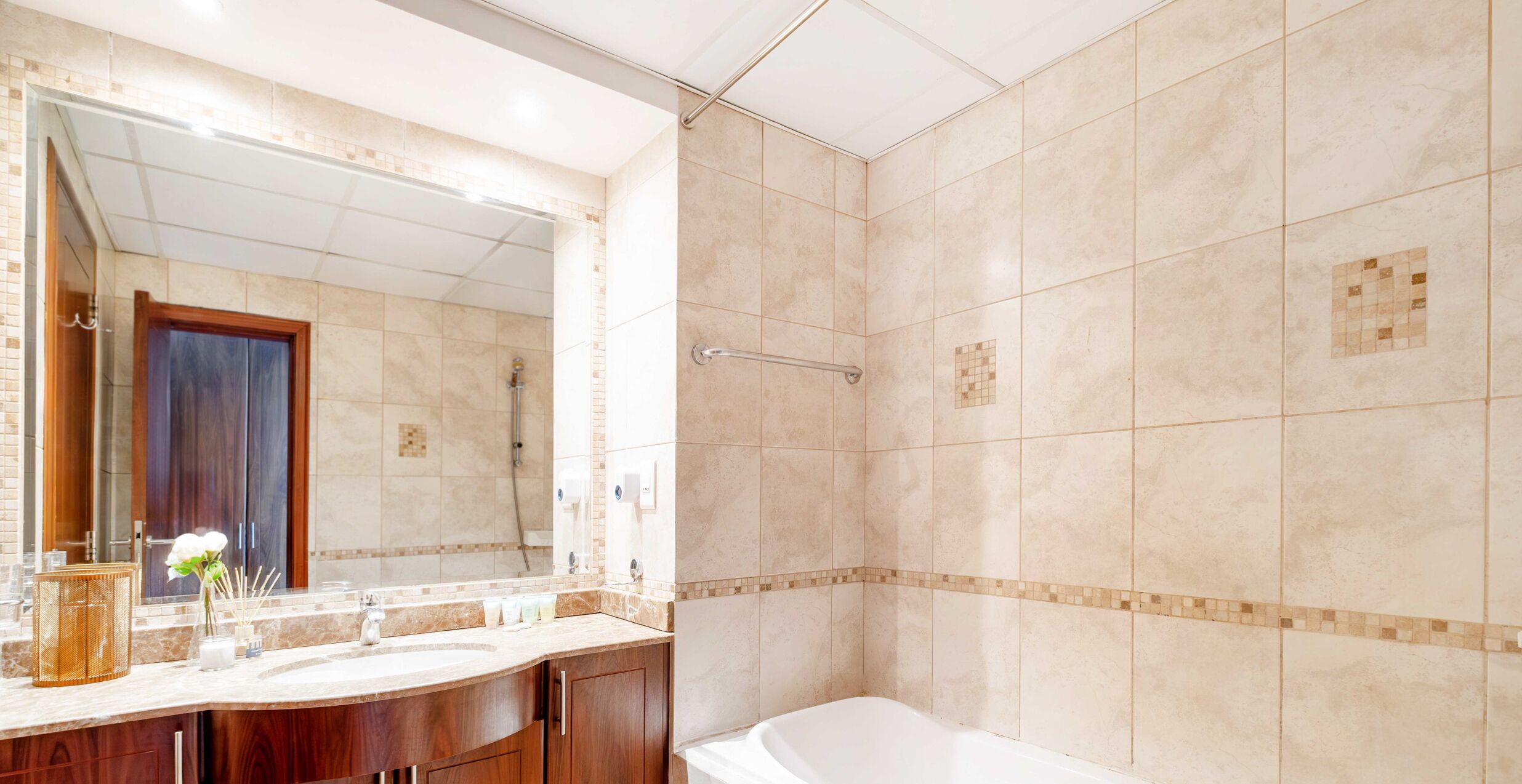 A bathroom with a large mirror, a bathtub, and a shower area.