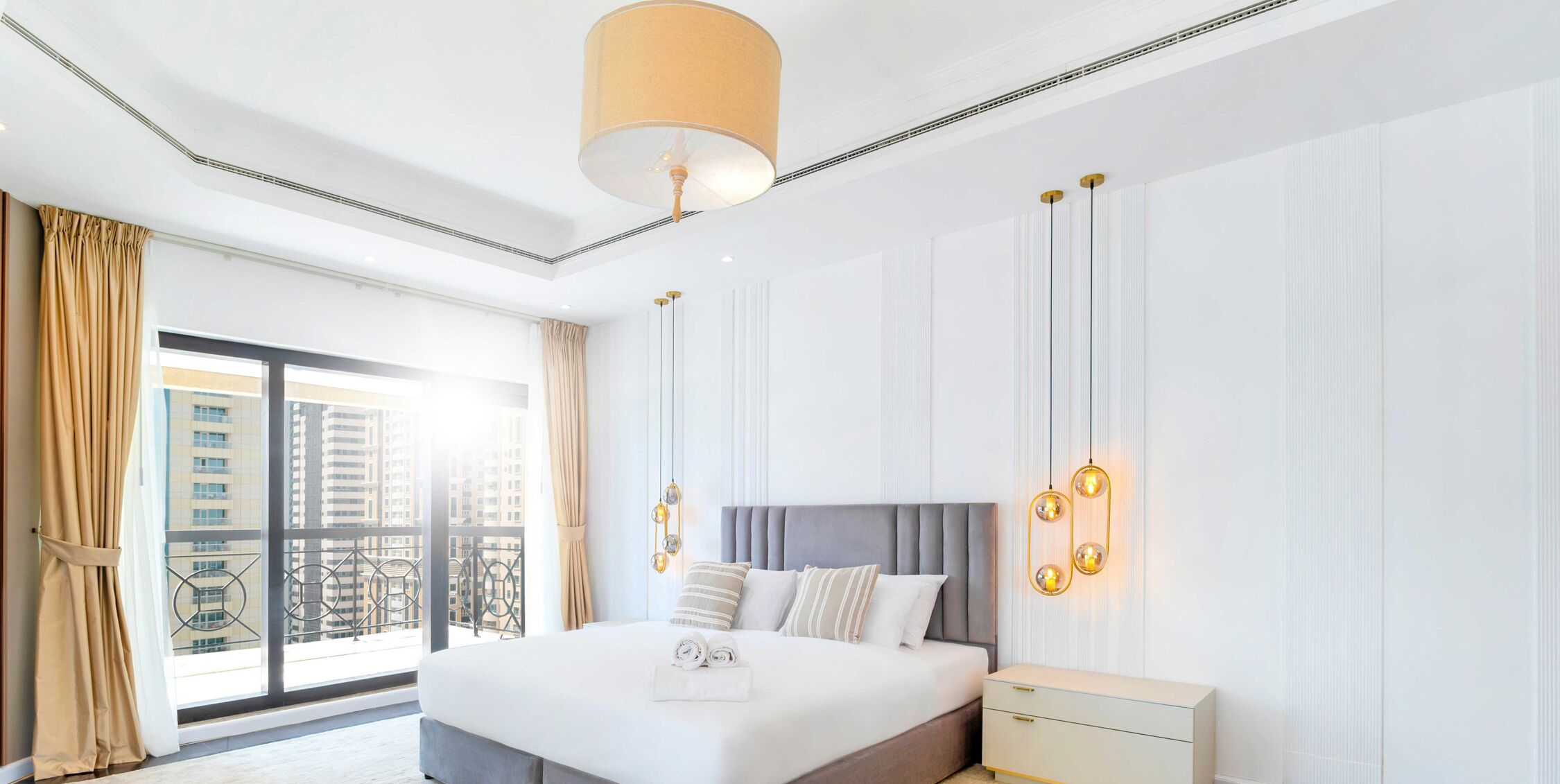 Ein modernes Hotelzimmer mit einem großen Bett, einem Nachttisch und Blick auf die Stadt durch das Fenster.
