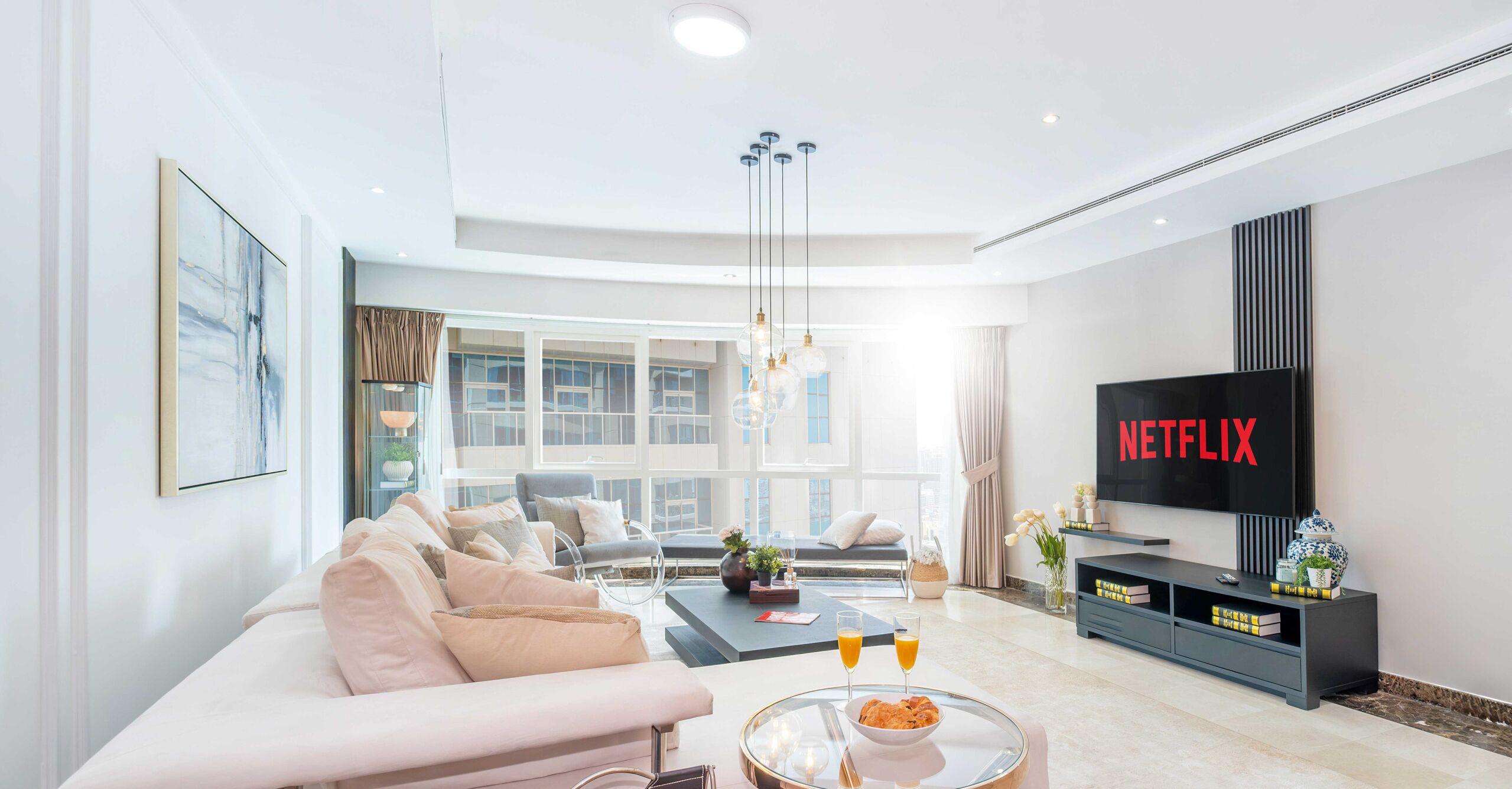 A modern living room with a sofa, coffee table, and a flat-screen TV displaying "NETFLIX".