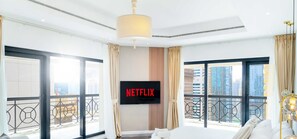 Une chambre d’hôtel avec un grand lit, un téléviseur fixé au mur et un balcon offrant une vue sur la ville.