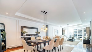 Een moderne eetkamer met een lange tafel, meerdere stoelen en hanglampen.