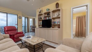 Una sala de estar con una silla roja, sofás color crema, una mesa de centro y un televisor sobre un mueble.
