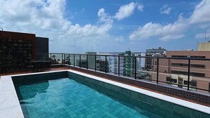 Ein Pool auf dem Dach mit klarem, blauem Wasser, umgeben von einem Glasgeländer.