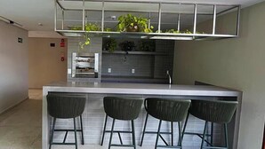 Eine moderne Küche mit einer zentralen Kochinsel, drei Barhocker und einem eingebauten Grill.