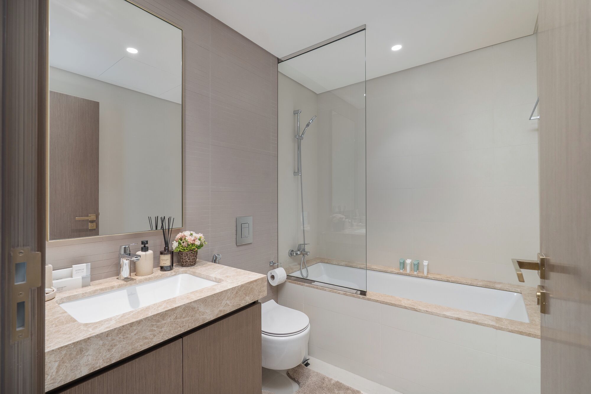 A modern bathroom with a large mirror, a sink, a toilet, and a glass-enclosed shower.