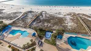 An aerial view of a beach resort with multiple swimming pools, sun loungers, and a sandy beach. - Phoenix East 1411 3 Bedroom Condo (Orange Beach)
