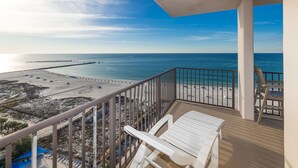 A balcony with a view of a beach, a wooden deck, and a railing. - Phoenix East 1411 3 Bedroom Condo (Orange Beach)
