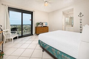 Une chambre à coucher comprenant un lit, une commode, une chaise, un téléviseur et un balcon avec vue.