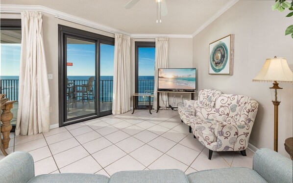 Un balcon avec vue sur la mer, un canapé, une télévision et une lampe.
