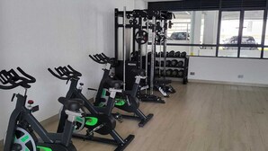 A gym with stationary bikes, weight machines, and dumbbells. - leo residence (Nairobi)
