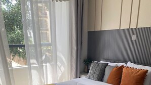 A neatly made bed with a white and yellow bedspread, grey headboard, and multiple pillows. - leo residence (Nairobi)