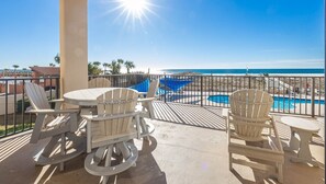 Enjoy the ocean view from this balcony, featuring a round table and four Adirondack chairs.
