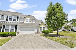 A two-story residential house with a garage, a driveway, and a well-maintained lawn.
