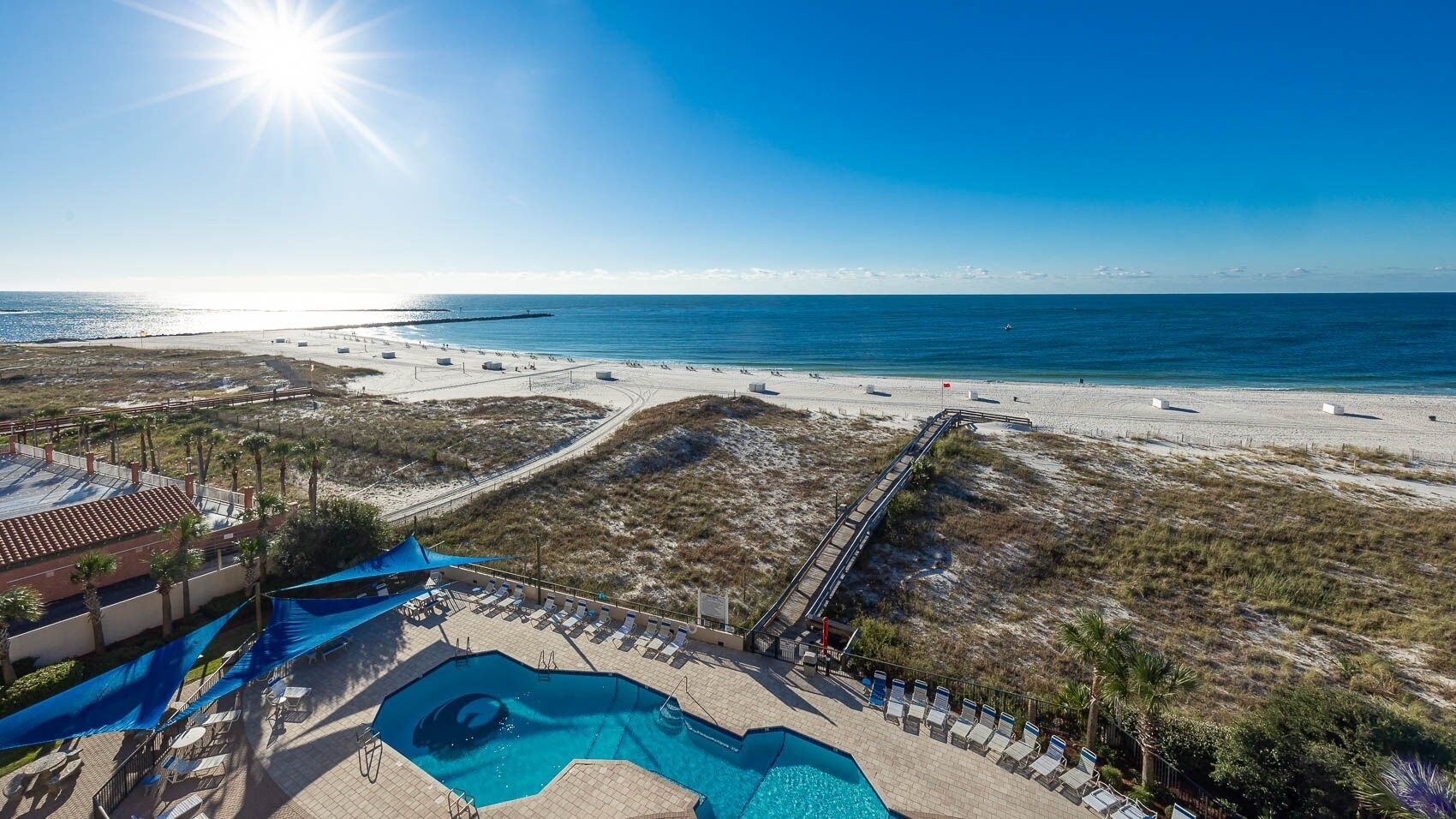 A beach resort with a swimming pool, beach access, and a view of the ocean.