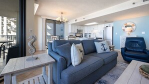 Ein modernes Wohnzimmer mit einem grauen Sofa, einem weißen Beistelltisch und einem blauen Sessel.