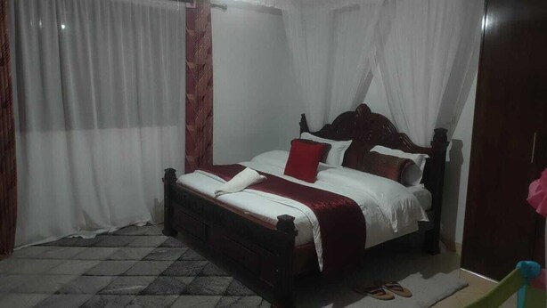 Un dormitorio con cama, cortinas y cabecera de madera.