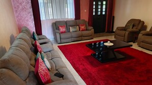 Una sala de estar con un sofá, un tapete rojo y una mesa de centro negra.