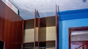 Un armario de madera con varios estantes y una puerta, situado junto a una pared azul y una puerta de madera.