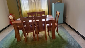 Un comedor con una mesa y sillas de madera, un refrigerador azul y una ventana con cortinas.