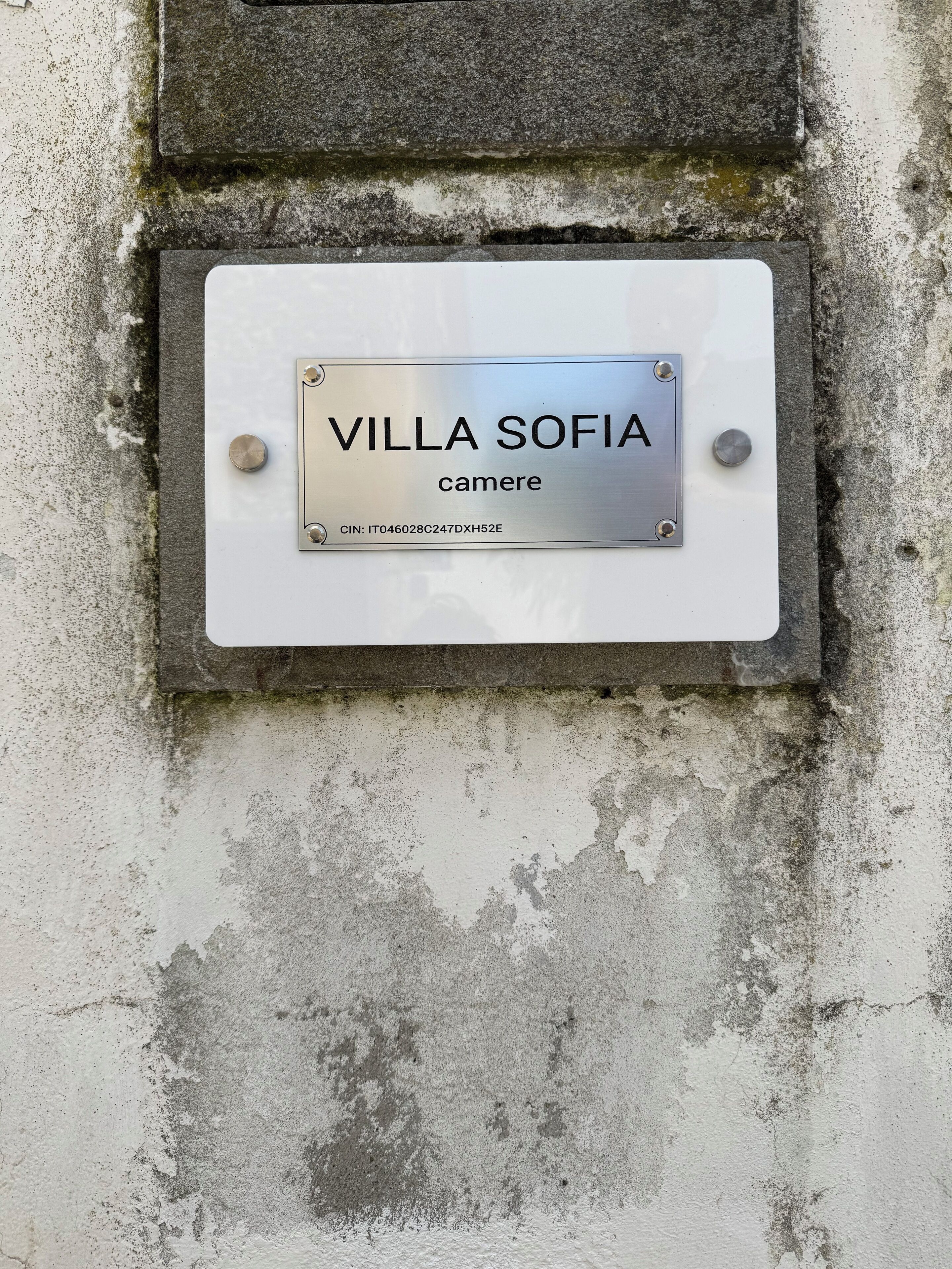 A metal plaque with "VILLA SOFIA" and "camere" on a weathered wall.