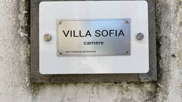 A metal plaque with "VILLA SOFIA" and "camere" on a weathered wall.