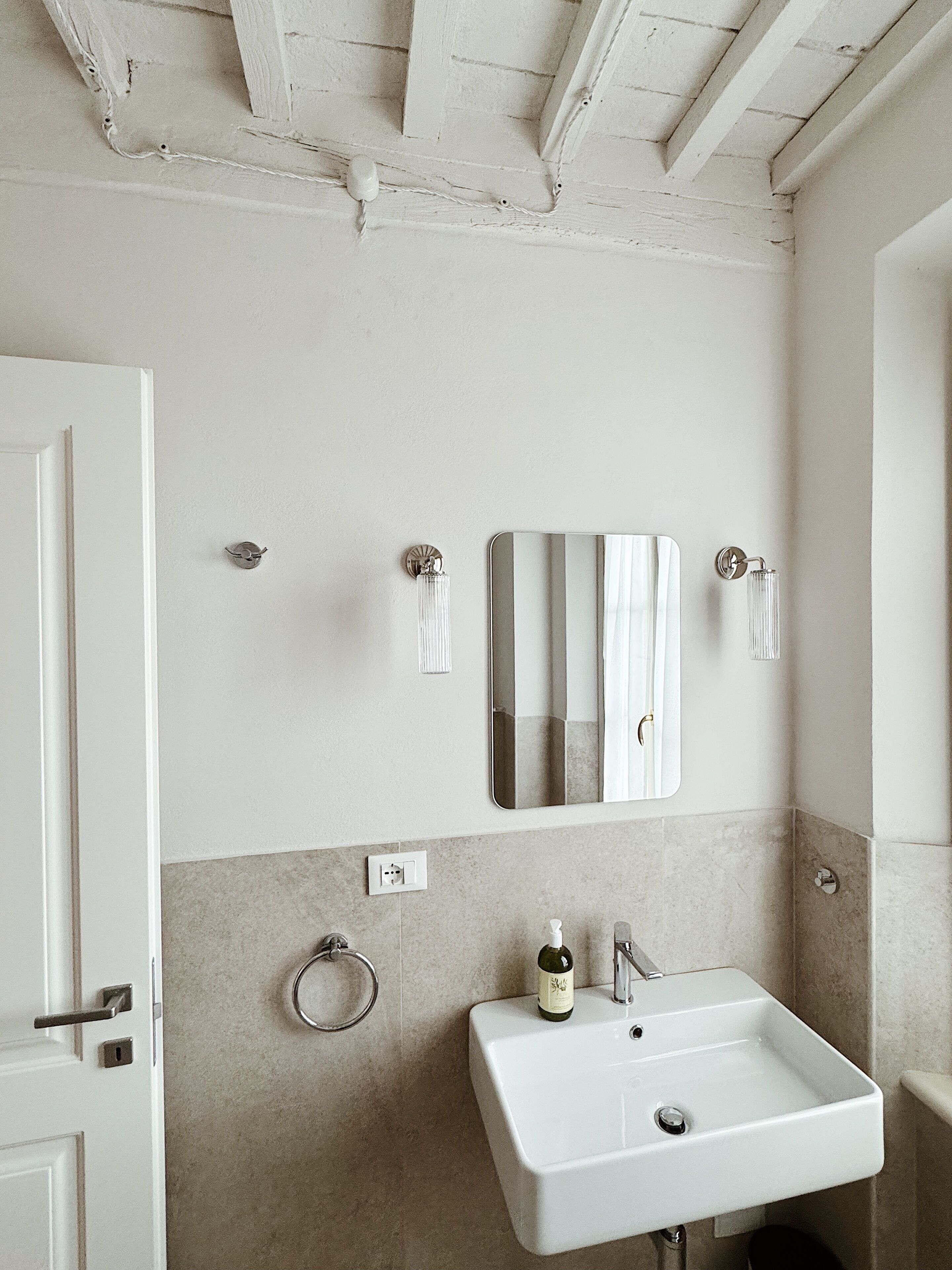 Ein Badezimmer mit einem weißen Waschbecken, einem Spiegel und einer Tür.
