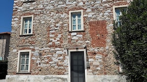 A multi-story stone building with a central entrance, multiple windows, and a gravel driveway. - Villa Sofia (Querceta)