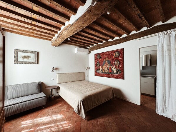 Une chambre à coucher avec un lit, une chaise, un tableau et un miroir.
